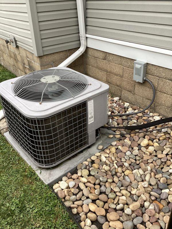# HVAC Maintenance - Cooling System Service

Performed complimentary preventive maintenance cleaning on residential split-system air conditioning unit as part of new membership enrollment. Conducted thorough inspection of outdoor condenser unit, which is properly installed on concrete pad with appropriate clearances and surrounded by river rock landscaping for drainage. Verified electrical disconnect box is accessible and refrigerant lines are properly secured along exterior wall. Cleaned condenser coils and removed debris from unit exterior and surrounding area. Inspected fan grille and protective guard for proper operation. Confirmed unit is level on concrete platform and all components are secure. System is operating within normal parameters with no immediate service needs identified at this time.