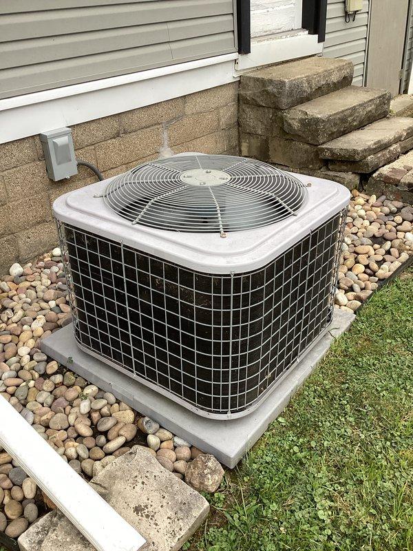 # HVAC Maintenance - Cooling System Service

Performed complimentary preventive maintenance cleaning on residential split-system air conditioning unit as part of new membership enrollment. Conducted thorough inspection of outdoor condenser unit, which is properly installed on concrete pad with appropriate clearances and surrounded by river rock landscaping for drainage. Verified electrical disconnect box is accessible and refrigerant lines are properly secured along exterior wall. Cleaned condenser coils and removed debris from unit exterior and surrounding area. Inspected fan grille and protective guard for proper operation. Confirmed unit is level on concrete platform and all components are secure. System is operating within normal parameters with no immediate service needs identified at this time.