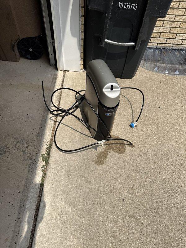 Responded to emergency water leak from reverse osmosis system in kitchen. Upon arrival, customer had already shut off main water supply to prevent further water damage. Inspected RO unit and identified failed connection causing water spray. Disconnected and removed malfunctioning reverse osmosis system from under-sink location. Relocated unit to garage area for temporary storage. Secured all water lines and verified main water supply could be safely restored to residence. System requires replacement or repair of pressure tank and valve assembly connections before reinstallation.