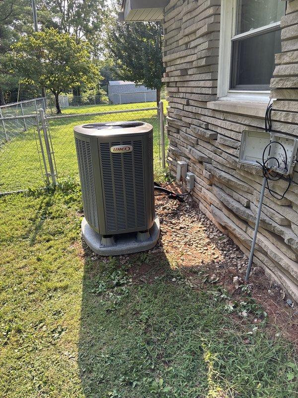 Completed full Lennox heat pump system installation at residential property. New outdoor condensing unit installed on concrete pad adjacent to brick exterior with proper electrical connections and conduit routing. System tested and verified operational with temperature readings confirming proper performance at 57.5°F in conditioned space.