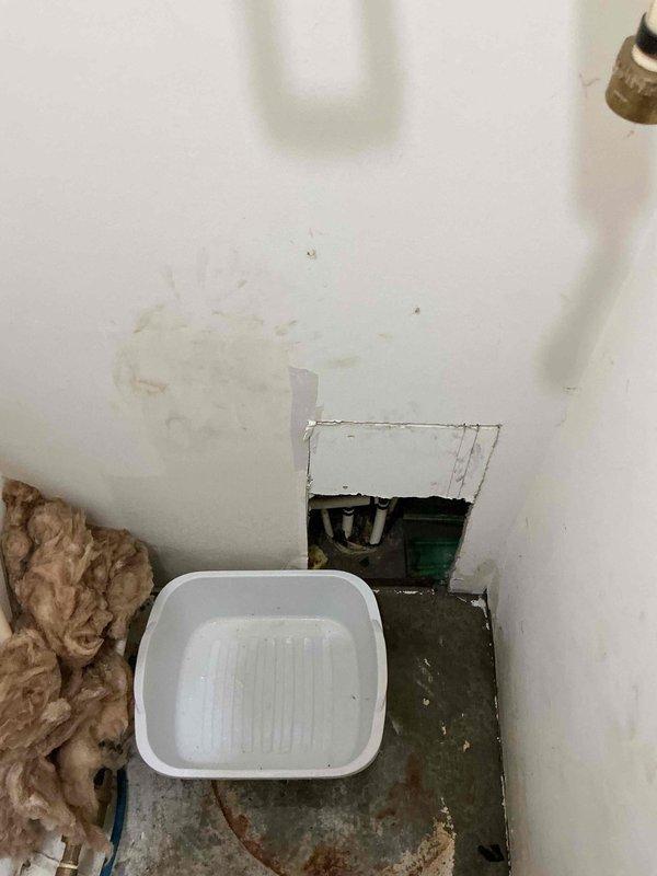 Responded to water leak investigation for unit experiencing moisture intrusion of unknown origin. Upon arrival, observed active water damage on interior ceiling with visible staining and discoloration indicating ongoing moisture penetration. Installed collection tray beneath compromised ceiling area and accessed ceiling cavity through existing panel to inspect for source. Inspected visible plumbing infrastructure including PVC supply lines, ball valve, and pressure regulator assembly with insulated piping sections. Unable to locate definitive leak source within the unit's accessible plumbing system or ceiling cavity. Documented conditions with photographs showing ceiling damage pattern and plumbing configuration. Leak may be originating from adjacent unit or building infrastructure requiring further investigation beyond scope of current access points.