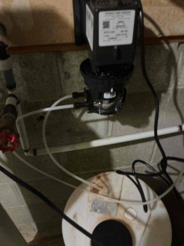 Responded to service callback for non-operational condensate pump system. Upon arrival, inspected HVAC condensate removal pump assembly mounted above collection basin and verified pump malfunction. Photographed existing installation showing black motorized pump unit with brass fittings, white discharge tubing with red-handled shutoff valve, and electrical connections. Noted visible water staining and discoloration in collection pan indicating previous drainage issues. Assessed pump motor, float switch mechanism, and associated plumbing connections to diagnose failure point and restore proper condensate removal operation.