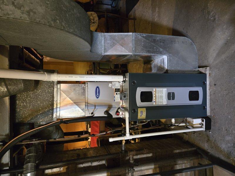 Conducted pre-installation site assessment of existing HVAC system in basement mechanical room. Documented current furnace/air handler configuration, including green-painted unit with sheet metal ductwork and galvanized rectangular plenum. Photographed ductwork layout showing multiple large diameter insulated ducts extending from main unit, PVC condensate drainage system, and copper piping installation. Evaluated electrical infrastructure by inspecting main panel box with circuit breakers, noting proximity to copper expansion piping and aging ceiling conditions. Verified accessibility and clearances for proposed equipment replacement work. Assessment confirmed feasibility of planned installation and identified necessary preparation requirements for upcoming system upgrade.