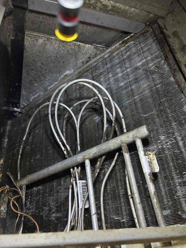 Responded to callback for water leaking from unit cover and saturating floor following previous service visit. Upon inspection, found evaporator coil assembly with significant dust and debris accumulation on fins and surrounding components. Inspected condensate drain system and identified drainage issue causing water overflow from drain pan. Cleared condensate drain line obstruction, verified proper drainage flow, and confirmed no refrigerant leaks present. System operating normally with no further water leakage observed.