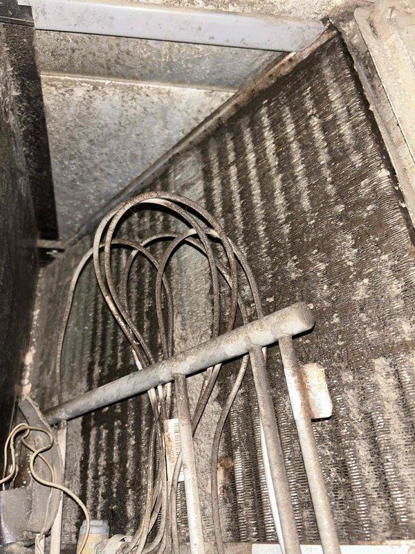 Responded to callback for water leaking from unit cover and saturating floor following previous service visit. Upon inspection, found evaporator coil assembly with significant dust and debris accumulation on fins and surrounding components. Inspected condensate drain system and identified drainage issue causing water overflow from drain pan. Cleared condensate drain line obstruction, verified proper drainage flow, and confirmed no refrigerant leaks present. System operating normally with no further water leakage observed.