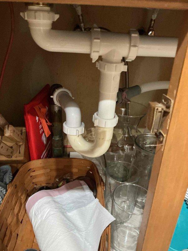 Completed annual plumbing inspection of residential property, examining all accessible water supply lines, shut-off valves, and drain assemblies. Inspected kitchen sink P-trap configuration with garbage disposal connections and water heater installation including hot and cold supply valves with flexible connectors, confirming all components are functioning properly with no visible leaks or deterioration detected.