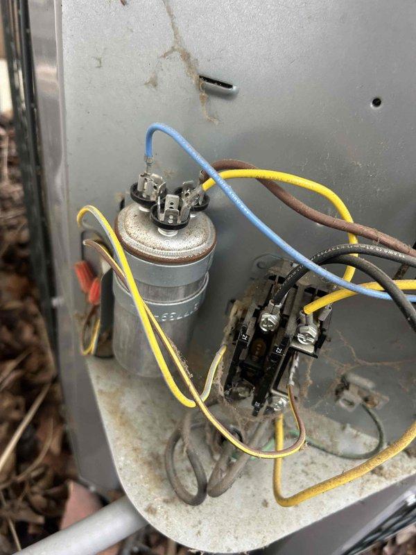 Responded to no cooling complaint on 9-year-old air conditioning system with outdoor fan not operating. Diagnosed failed dual run capacitor causing condenser fan motor failure. Replaced defective JARD capacitor with new unit, tested electrical connections with multimeter to verify proper voltage and amperage. Cleared debris accumulation from around outdoor unit, cycled system, and confirmed condenser fan motor operation and proper cooling restored.