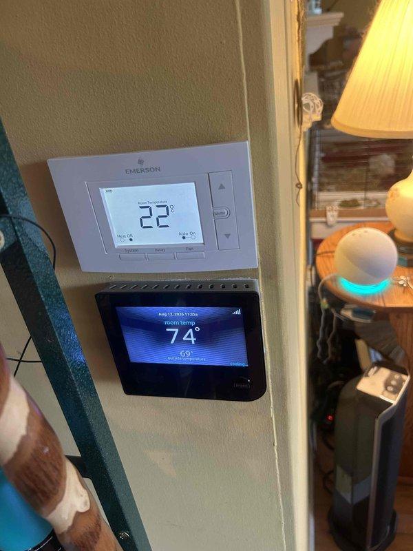 Responded to no cooling call and performed diagnostic evaluation of residential HVAC system. Inspected attic-mounted air handler and ductwork, verified thermostat operation showing dual-zone control with Emerson unit and digital touchscreen displaying 74°F room temperature with 69°F setpoint. Documented equipment location and system configuration for service records.