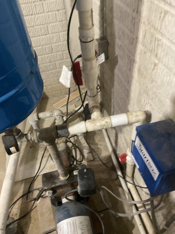 Conducted estimate evaluation on 20-year-old geothermal heating and cooling system with failed storage tank requiring replacement. Inspected mechanical room installation including geothermal heat pump unit, associated piping infrastructure with mix of PVC and aged metal components showing corrosion, and pump assembly with multiple pipe connections. Assessed existing system configuration and documented equipment condition through photographs to prepare replacement estimate for customer.