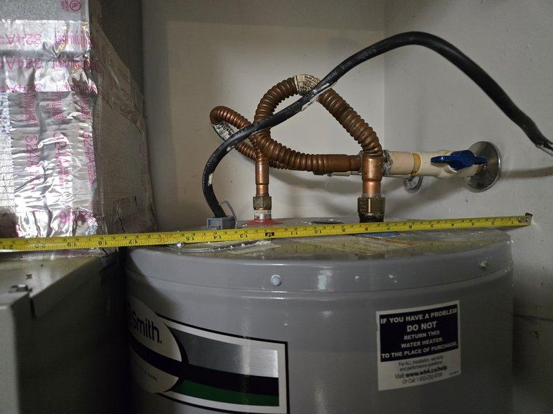 Conducted site visit to assess installation requirements for 40-gallon heat pump water heater. Measured available space dimensions in utility area to verify proper clearance for unit placement and documented existing plumbing connections including copper flex lines and shutoff valve configuration. Confirmed A.O. Smith water heater positioning and photographed installation area specifications for equipment compatibility verification.