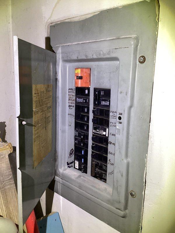 Responded to no cooling complaint on 20-25 year old AC system with indoor temperature stuck at 79°F. Upon arrival, inspected electrical panel and thermostat operation as customer reported previous burnt wire issue. Photographed electrical panel showing main breaker and circuit configuration, as well as Crane thermostat with digital display. Evaluated system electrical connections, breaker status, and thermostat functionality to diagnose cooling failure on aging outdoor unit.