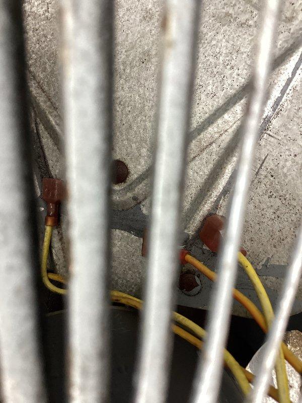 Responded to service call for rattling noise from AC unit, which customer had turned off prior to arrival. Upon inspection, found outdoor condenser unit showing significant weathering and age-related deterioration, with visible rust staining on top panel and debris accumulation around cabinet. Documented unit condition with photographs showing electrical wiring connections behind protective grating and overall exterior condition of condenser. Unit remains offline pending further diagnostic work or repair approval.
