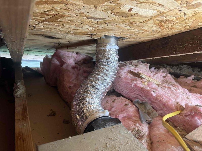 Completed bathroom ventilation system readjustment and warranty inspection. Accessed crawl space to reposition and secure flexible aluminum ductwork that had become compressed and displaced, restored proper insulation coverage around duct runs, and verified grille mounting and airflow at ceiling register. System tested and confirmed operating within manufacturer specifications.