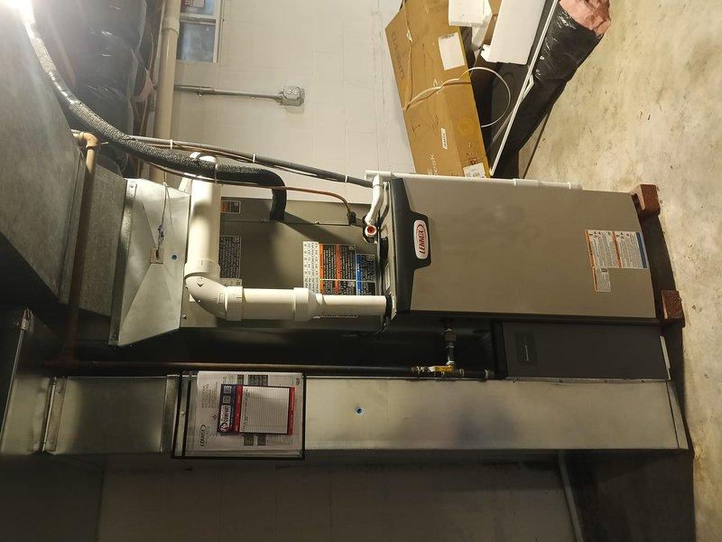 Completed full HVAC system installation consisting of Lennox air conditioning unit and gas furnace in basement utility area. Installed new furnace with proper venting using white PVC piping, connected refrigerant lines, and integrated flexible ductwork to existing distribution system. Mounted and tested Defender low-level carbon monoxide monitor in accordance with safety codes, verified digital display functionality and alarm system operation reading 0.0 ppm at completion.