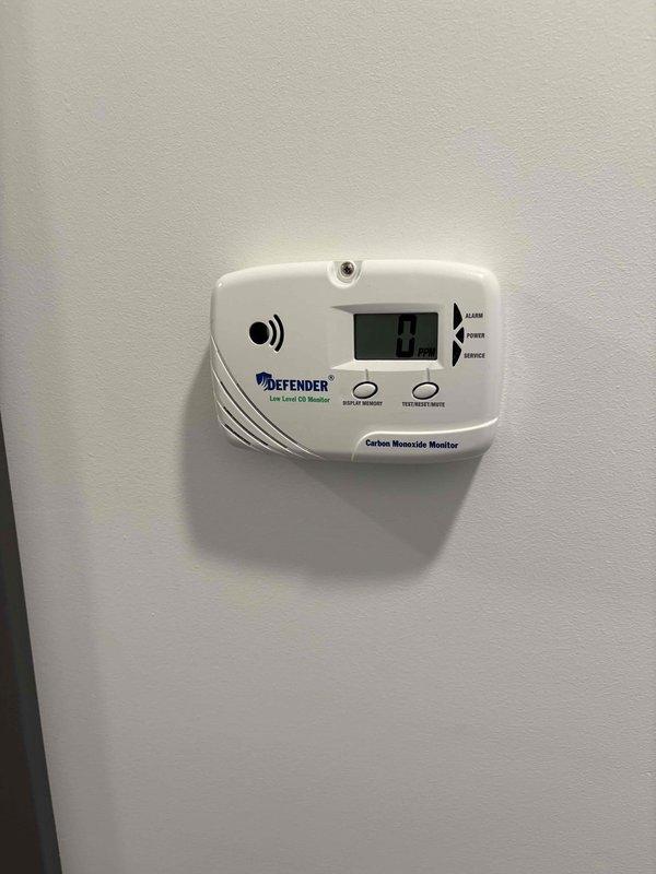 Completed full HVAC system installation consisting of Lennox air conditioning unit and gas furnace in basement utility area. Installed new furnace with proper venting using white PVC piping, connected refrigerant lines, and integrated flexible ductwork to existing distribution system. Mounted and tested Defender low-level carbon monoxide monitor in accordance with safety codes, verified digital display functionality and alarm system operation reading 0.0 ppm at completion.