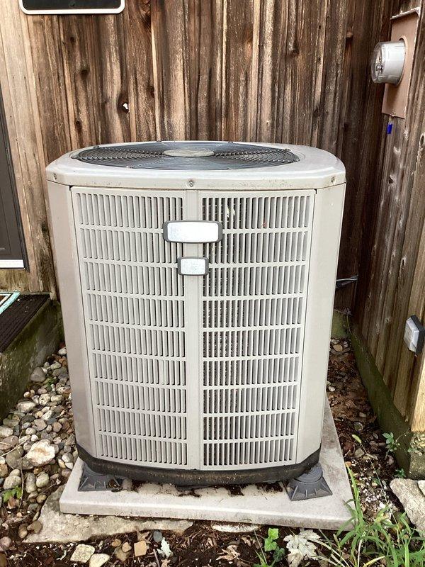 # HVAC Service Report

Responded to emergency no-cooling call for residential air conditioning system. Upon arrival, found outdoor condenser unit operational with fan running and indoor air handler circulating air through ductwork, but system failing to produce cool air. Conducted diagnostic inspection of both indoor and outdoor components to identify root cause of cooling failure.

Examined outdoor condenser unit positioned against perimeter fence, confirming compressor operation and proper airflow through condenser coils. Verified electrical connections at disconnect box and assessed refrigerant line conditions. Indoor inspection revealed air handler cabinet with accessible filter compartment and blower assembly functioning normally for air circulation.

Based on system age being unknown and observed conditions, likely causes for cooling failure include refrigerant leak requiring recharge, failed capacitor affecting compressor performance, or potential compressor failure. Documented 
