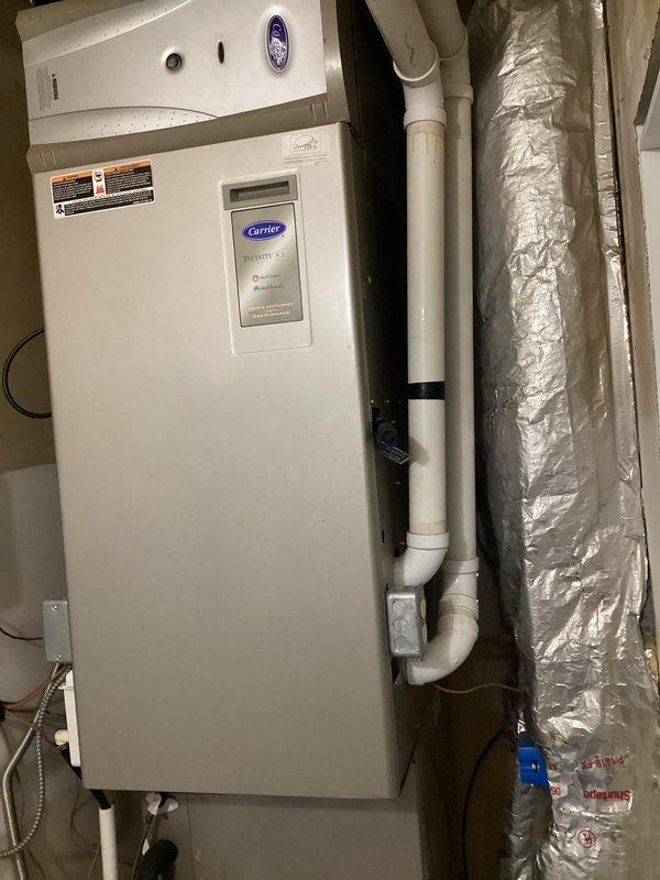 Performed comprehensive diagnostic evaluation of Carrier Infinity system for new homeowner experiencing multiple operational concerns. Identified critical issues including improper air intake configuration drawing exclusively from garage, missing air filter, inadequate duct sealing, existing humidifier kit requiring removal, compromised condensate drainage causing excessive moisture accumulation in equipment closet, and suspected black mold growth at base of air handler unit. Documented system conditions and deficiencies with photographic evidence showing thermostat operation and overall equipment installation. Provided assessment of necessary corrective actions including ductwork modifications, condensate drain repair, mold remediation requirements, and proper air filtration installation to restore system to safe and efficient operation.