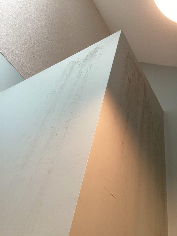 Responded to moisture concern related to HVAC system in closet. Upon inspection, found vertical water streaking pattern on adjacent wall surface originating from upper portion of unit. Verified air conditioning system operating within normal parameters with no signs of condensation, perspiration, or elevated humidity levels in closet space. Confirmed no excess heat generation from equipment. Documented conditions with photographs showing wall discoloration pattern and installed HVAC unit configuration. Staining pattern appeared inconsistent with typical HVAC-related moisture issues, suggesting alternative water source from above unit rather than condensate or refrigerant system malfunction.