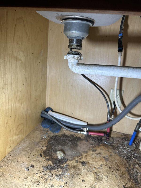 Responded to service call for kitchen sink drain pipe that had come loose from the basin. Upon inspection, found the drain assembly connection had separated, causing potential leakage. Secured and properly reconnected the drain pipe to the sink strainer assembly, ensuring all threaded connections were tight and properly sealed. Noted evidence of previous water damage on cabinet floor from the loose connection. Tested system for proper drainage and verified no active leaks present after repair.