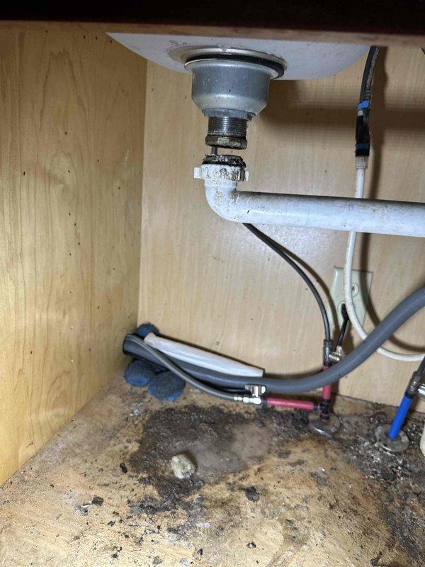 Responded to service call for kitchen sink drain pipe that had come loose from the basin. Upon inspection, found the drain assembly connection had separated, causing potential leakage. Secured and properly reconnected the drain pipe to the sink strainer assembly, ensuring all threaded connections were tight and properly sealed. Noted evidence of previous water damage on cabinet floor from the loose connection. Tested system for proper drainage and verified no active leaks present after repair.