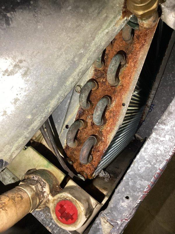 Responded to service call for water dripping from bottom of 16-year-old furnace unit. Upon inspection, discovered severely corroded heat exchanger with extensive rust deterioration throughout the serpentine coil channels, indicating significant age-related failure and compromised structural integrity. Documented equipment condition with photographs showing the rusted heat exchanger plate, deteriorated housing components, and associated copper refrigerant lines. The water leakage was attributed to condensate drainage issues related to the corroded evaporator coil assembly. Advised customer of equipment condition and recommended full system replacement due to the extent of corrosion and age of unit, as the compromised heat exchanger poses potential safety concerns and repair would not be cost-effective given the overall deterioration of the system.