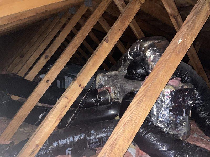 Provided second opinion evaluation on existing HVAC system installation in attic space. Assessed previous installation work and confirmed multiple deficiencies requiring corrective action, including missing drain pan beneath air handler unit, improperly angled condensate drain lines preventing adequate drainage, and potential flue pipe replacement needs. Documented current system configuration with photographic evidence showing air handler placement, ductwork installation with R-4.2 insulation, and existing PVC drain line routing. Recommended system would require lifting air handler unit, disconnecting evaporator coils, installing proper drain pan, and re-pitching drain lines to ensure correct drainage angle and code compliance.