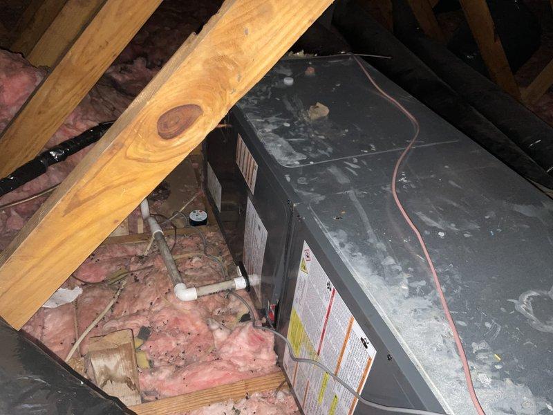 Provided second opinion evaluation on existing HVAC system installation in attic space. Assessed previous installation work and confirmed multiple deficiencies requiring corrective action, including missing drain pan beneath air handler unit, improperly angled condensate drain lines preventing adequate drainage, and potential flue pipe replacement needs. Documented current system configuration with photographic evidence showing air handler placement, ductwork installation with R-4.2 insulation, and existing PVC drain line routing. Recommended system would require lifting air handler unit, disconnecting evaporator coils, installing proper drain pan, and re-pitching drain lines to ensure correct drainage angle and code compliance.