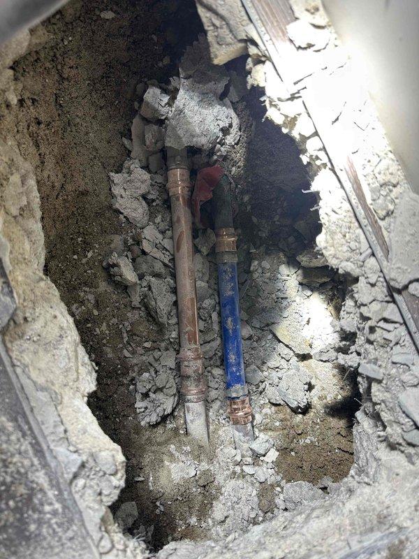 Performed sonic leak detection to locate active slab leak beneath concrete floor. Excavated and removed concrete section to expose damaged copper water lines. Identified and extracted two severely corroded copper pipe segments showing extensive oxidation and deterioration. Repaired compromised plumbing system by replacing failed sections with new fittings and connections. Restored water line integrity to eliminate leak and prevent further water damage to foundation.