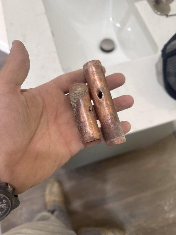 Performed sonic leak detection to locate active slab leak beneath concrete floor. Excavated and removed concrete section to expose damaged copper water lines. Identified and extracted two severely corroded copper pipe segments showing extensive oxidation and deterioration. Repaired compromised plumbing system by replacing failed sections with new fittings and connections. Restored water line integrity to eliminate leak and prevent further water damage to foundation.