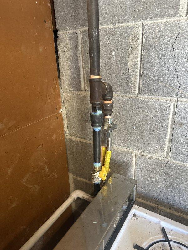 Completed installation of tankless water heater in basement utility area, including all necessary gas line connections with shut-off valve, copper supply piping with PVC vent connections, and pressure relief valve. Unit was mounted securely to wooden wall surface and all plumbing connections were tested for proper operation and leak-free performance.