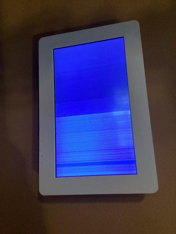 Responded to service call for digital thermostat displaying solid lines and blinking screen while AC unit continued operating. Upon inspection, confirmed thermostat display malfunction showing horizontal scan lines and blue screen illumination, indicating internal display failure. Documented equipment specifications and thermostat condition for service records.