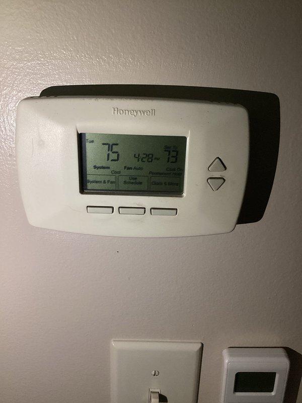 Responded to no-cooling call on residential air conditioning system. Upon arrival, performed diagnostic evaluation of outdoor condenser unit and indoor thermostat controls. Thermostat displayed active cooling mode with setpoint at 73 degrees while ambient temperature read 75 degrees, indicating system was calling for cooling but not achieving desired temperature. Inspected outdoor condenser unit positioned on concrete pad with electrical disconnect box and confirmed unit was not operating. Conducted electrical testing at disconnect and verified power supply to unit. Diagnosed failed capacitor preventing compressor and condenser fan motor from starting. Replaced dual-run capacitor with proper MFD-rated component. Tested system operation and confirmed compressor engagement and condenser fan rotation. Verified proper amp draw on both compressor and fan motor. System cycled properly and began producing cold air at supply registers. Documented equipment condition with photographs of outdoor