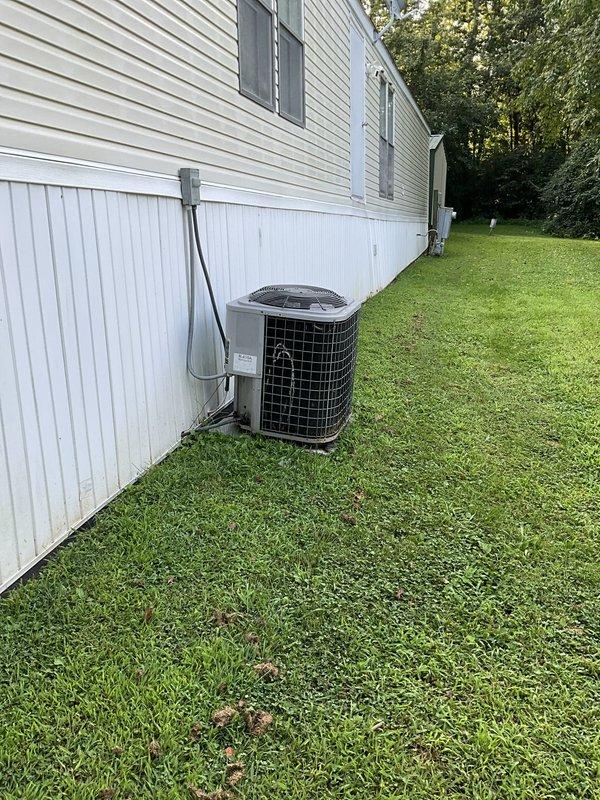 Conducted comprehensive site assessment of existing HVAC system for mobile home replacement estimate. Evaluated outdoor condensing unit positioned on concrete pad with electrical disconnect and protective grille cage. Inspected interior Coleman furnace installation located in hallway closet with standard venting configuration. Documented current equipment specifications, electrical connections, and existing infrastructure to provide competitive replacement proposal. Assessed accessibility for equipment removal and new system installation in manufactured housing environment.