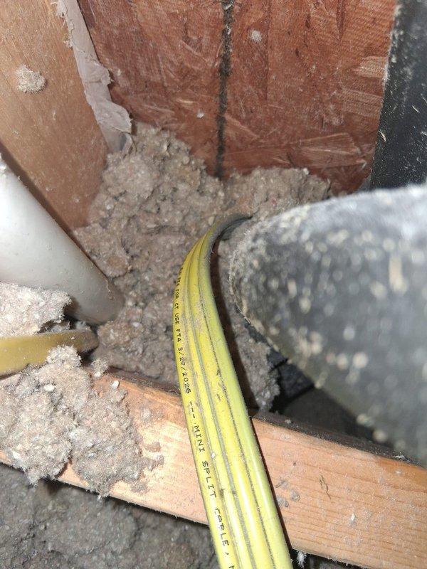 Responded to warranty call for mini split system leaking down wall due to suspected uninsulated copper refrigerant line. Upon inspection, located exposed copper line section in attic/crawl space area where insulation was missing or improperly installed at structural junction point. Documented conditions with photos showing wooden framing, refrigerant lines, and condensation accumulation. Identified gap in line insulation as source of condensate formation on exposed copper, causing water to run down interior wall. Corrected insulation deficiency on refrigerant line to prevent future condensation and leakage issues, ensuring proper coverage at all connection points and structural penetrations per manufacturer specifications.
