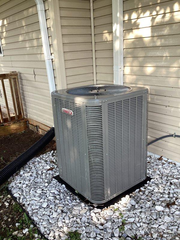 # HVAC Maintenance Report

Completed monthly preventive maintenance service on residential Lennox central air conditioning system. Performed comprehensive cooling season inspection of outdoor condensing unit located on exterior gravel pad. 

Conducted visual assessment of unit cabinet, verifying structural integrity of housing and louver panels. Inspected fan grille and top discharge assembly for proper clearance and debris accumulation. Examined electrical conduit routing and mounting along building exterior, confirming secure attachment and proper weatherproofing. Verified condensate drainage line positioning and flow path away from unit foundation.

Assessed equipment placement on gravel bed, noting adequate drainage substrate and minimal vegetation encroachment. Confirmed unit levelness on pad and inspected for settling or displacement. Evaluated surrounding clearances for proper airflow and service access per manufacturer specifications.

Documented equipment condition through pho