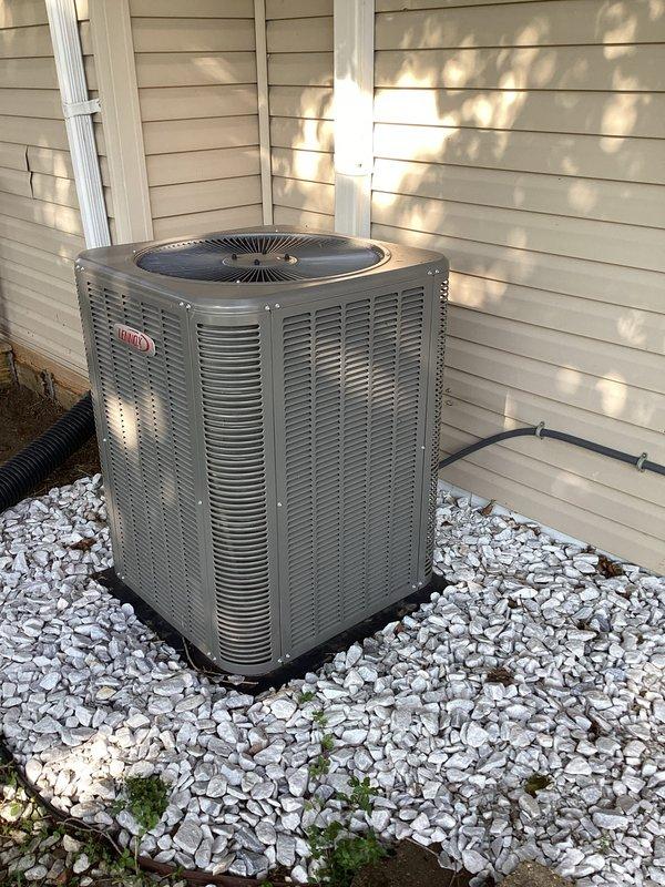 # HVAC Maintenance Report

Completed monthly preventive maintenance service on residential Lennox central air conditioning system. Performed comprehensive cooling season inspection of outdoor condensing unit located on exterior gravel pad. 

Conducted visual assessment of unit cabinet, verifying structural integrity of housing and louver panels. Inspected fan grille and top discharge assembly for proper clearance and debris accumulation. Examined electrical conduit routing and mounting along building exterior, confirming secure attachment and proper weatherproofing. Verified condensate drainage line positioning and flow path away from unit foundation.

Assessed equipment placement on gravel bed, noting adequate drainage substrate and minimal vegetation encroachment. Confirmed unit levelness on pad and inspected for settling or displacement. Evaluated surrounding clearances for proper airflow and service access per manufacturer specifications.

Documented equipment condition through pho