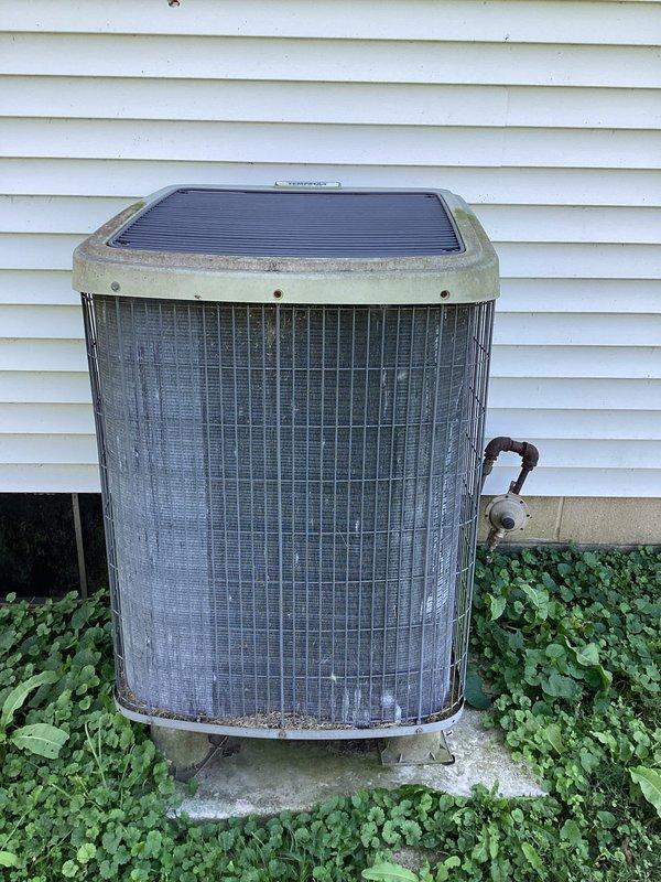 Responded to no cooling complaint on older residential air conditioning system. Found outdoor condensing unit fan motor operational but system not producing cold air. Thermostat set to 72°F cooling mode with current indoor temperature reading 77°F, confirming lack of cooling capacity. Performed diagnostic evaluation of condensing unit and refrigerant lines showing signs of age and oxidation on copper piping and service valves.