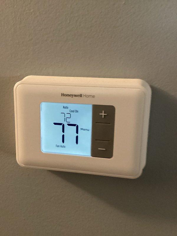 Responded to no cooling complaint on older residential air conditioning system. Found outdoor condensing unit fan motor operational but system not producing cold air. Thermostat set to 72°F cooling mode with current indoor temperature reading 77°F, confirming lack of cooling capacity. Performed diagnostic evaluation of condensing unit and refrigerant lines showing signs of age and oxidation on copper piping and service valves.
