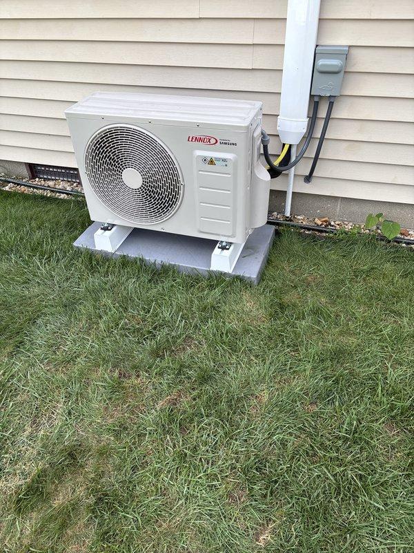 Completed installation of Lennox mini split system including outdoor condenser unit mounted on concrete pad and indoor air handler. Outdoor unit properly positioned on level concrete platform with electrical disconnect box and conduit installed per code requirements, verified system operational with temperature readings confirming 42.8°F output at indoor unit.