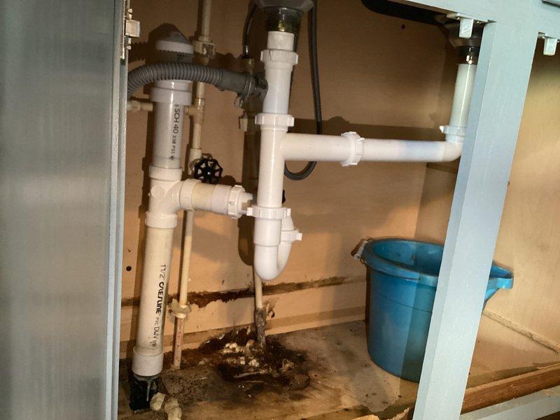 Returned to property to complete kitchen sink drain repiping project. Replaced deteriorated PVC drain assembly beneath kitchen sink, including new P-trap installation and vertical/horizontal drain connections. Addressed previous water leakage issues evidenced by cabinet floor staining. Verified proper drain function and seal integrity at sink strainer basket. All plumbing connections tested and confirmed leak-free upon completion.