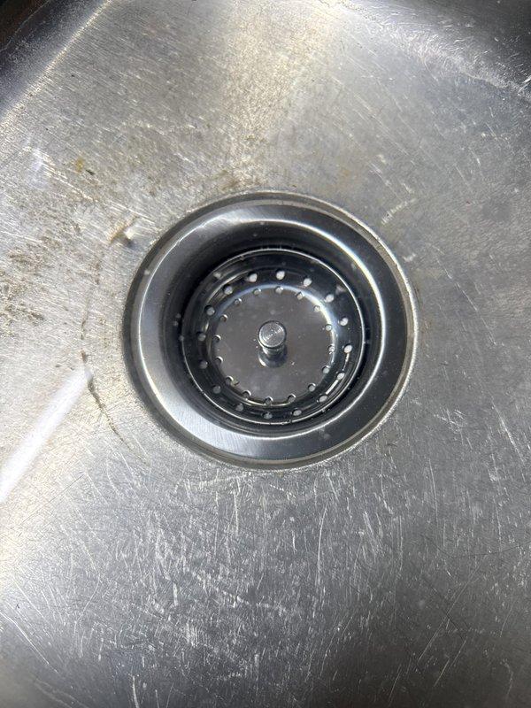 Returned to property to complete kitchen sink drain repiping project. Replaced deteriorated PVC drain assembly beneath kitchen sink, including new P-trap installation and vertical/horizontal drain connections. Addressed previous water leakage issues evidenced by cabinet floor staining. Verified proper drain function and seal integrity at sink strainer basket. All plumbing connections tested and confirmed leak-free upon completion.