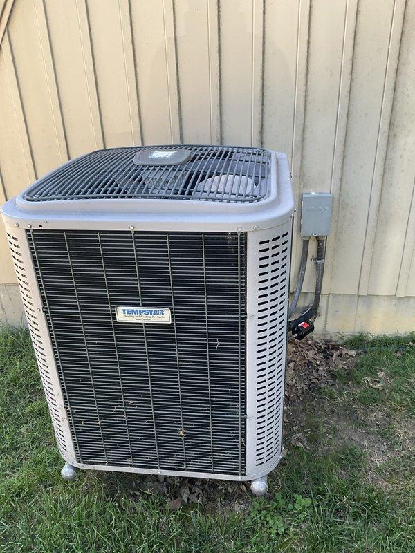 Conducted on-site evaluation of existing residential cooling system for replacement estimate. Customer reported ongoing reliability issues with current TempStar air conditioning unit. Assessed outdoor condenser unit condition, indoor ductwork assembly, and electrical connections. Documented equipment specifications and existing system configuration. Photographed outdoor condenser unit positioned against building exterior with electrical disconnect box, and interior vertical ductwork running floor to ceiling with associated electrical panel and refrigerant lines. Provided comprehensive replacement options and pricing to address customer's cooling system concerns.
