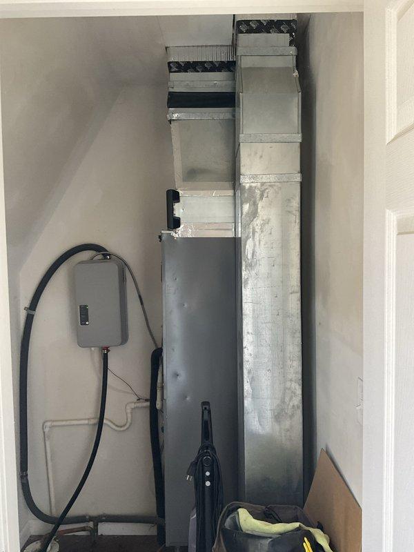 Conducted on-site evaluation of existing residential cooling system for replacement estimate. Customer reported ongoing reliability issues with current TempStar air conditioning unit. Assessed outdoor condenser unit condition, indoor ductwork assembly, and electrical connections. Documented equipment specifications and existing system configuration. Photographed outdoor condenser unit positioned against building exterior with electrical disconnect box, and interior vertical ductwork running floor to ceiling with associated electrical panel and refrigerant lines. Provided comprehensive replacement options and pricing to address customer's cooling system concerns.