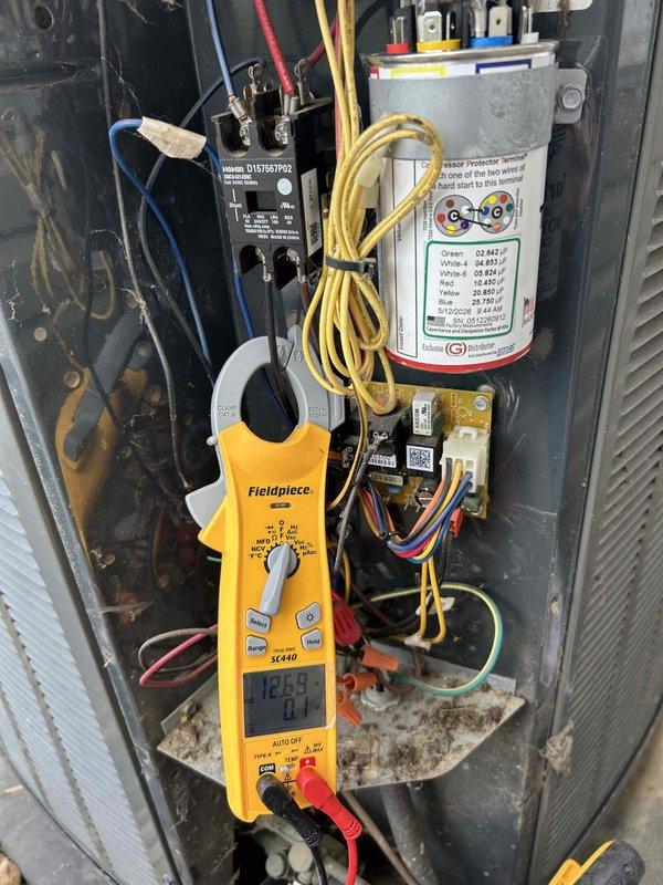 Responded to no cooling call and performed diagnostic evaluation of outdoor air conditioning unit. Upon inspection, found heavily corroded capacitor with significant rust buildup on terminals affecting electrical connections. Tested system amperage reading 12.59 amps and verified capacitor failure as primary cause of system malfunction. Identified deteriorated wiring connections and compromised electrical components within control panel requiring immediate attention to restore proper system operation.