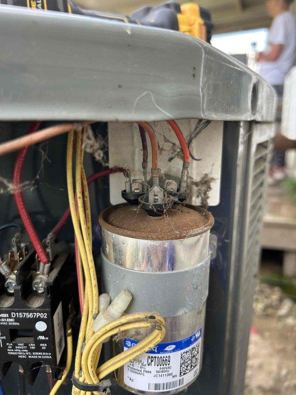 Responded to no cooling call and performed diagnostic evaluation of outdoor air conditioning unit. Upon inspection, found heavily corroded capacitor with significant rust buildup on terminals affecting electrical connections. Tested system amperage reading 12.59 amps and verified capacitor failure as primary cause of system malfunction. Identified deteriorated wiring connections and compromised electrical components within control panel requiring immediate attention to restore proper system operation.