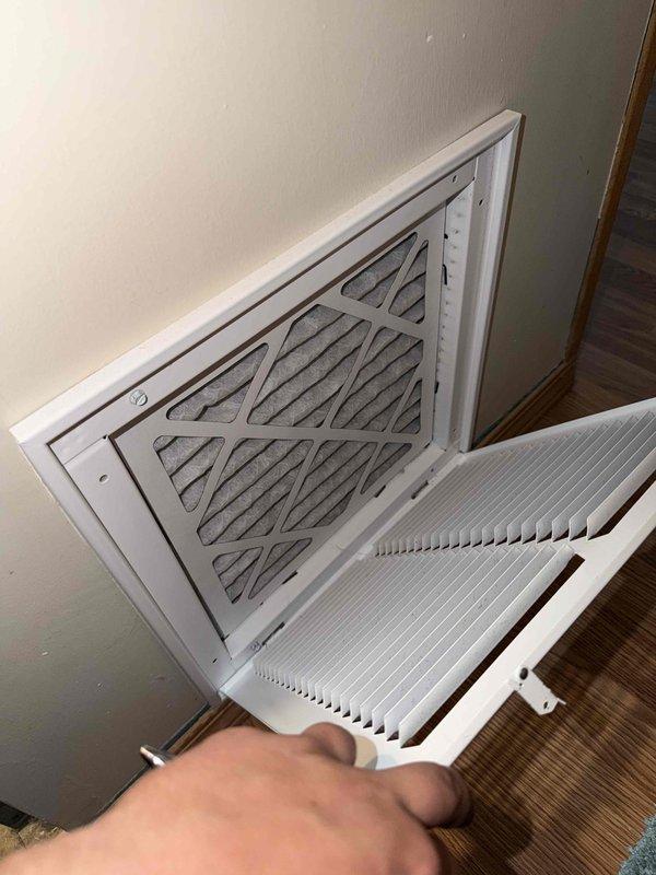 Completed routine HVAC maintenance under active CCC basic coverage agreement. Measured supply air temperature at 75°F using digital thermometer at return air grille, accessed and inspected 12x12x1 air filter through hinged return register, and documented system conditions with photos showing proper airflow measurements and filter access point.