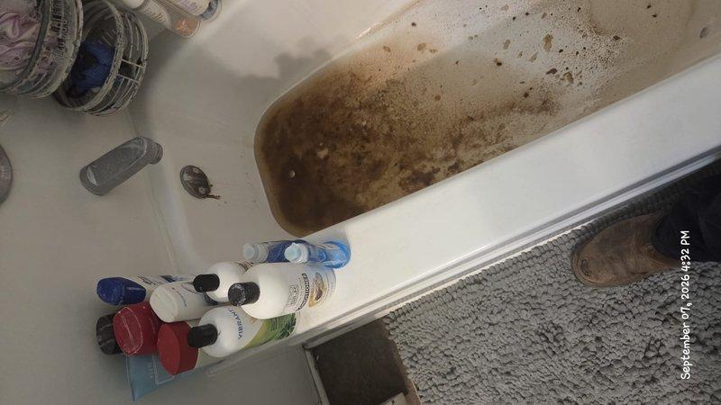 Responded to customer inquiry regarding bathtub water discoloration and sediment accumulation. Upon inspection, documented severe brown staining on tub interior surfaces and murky water containing visible sediment particles, indicating potential issues with water supply quality, corroded piping, or mineral deposits in the plumbing system. Photographed conditions to provide visual documentation of the discoloration pattern and sediment concentration for further diagnostic evaluation and recommended follow-up with qualified plumbing technician to assess water supply lines and determine source of contamination.