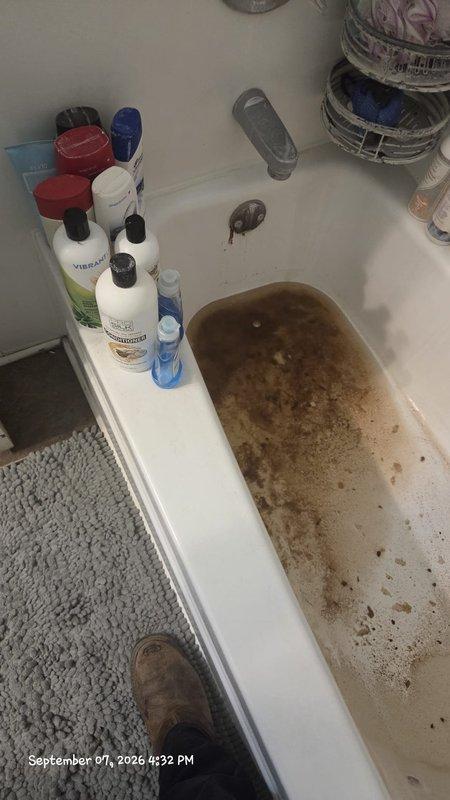 Responded to customer inquiry regarding bathtub water discoloration and sediment accumulation. Upon inspection, documented severe brown staining on tub interior surfaces and murky water containing visible sediment particles, indicating potential issues with water supply quality, corroded piping, or mineral deposits in the plumbing system. Photographed conditions to provide visual documentation of the discoloration pattern and sediment concentration for further diagnostic evaluation and recommended follow-up with qualified plumbing technician to assess water supply lines and determine source of contamination.