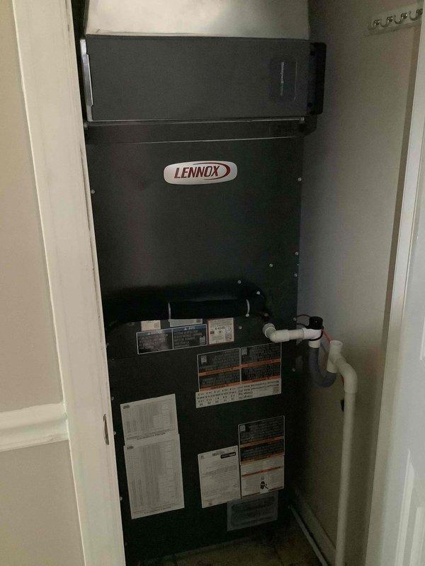 Completed full installation of Lennox heat pump system including indoor air handler unit positioned in utility closet and outdoor condensing unit installed on composite pad in exterior corner location. Indoor unit features proper PVC condensate drainage and venting configuration with all manufacturer labels and technical specifications clearly visible, while outdoor condenser is professionally positioned on gravel base with electrical conduit and refrigerant line set connections completed per manufacturer specifications.