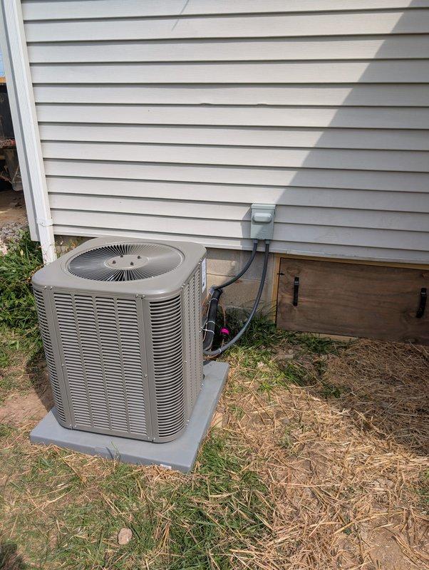Completed full system installation of Lennox air conditioning condenser unit and evaporator coil in downflow configuration. Positioned outdoor condenser on concrete pad adjacent to structure, secured refrigerant lines and electrical conduit to exterior wall with proper routing through disconnect box, and installed evaporator coil in downflow orientation within indoor air handler. Installed Honeywell Home digital programmable thermostat for system control, completed all refrigerant line connections, performed system startup and verification of proper operation.